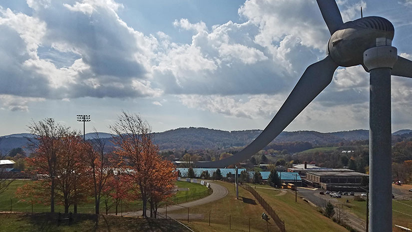 A small wind turbine in the forefront of a sporting field complex