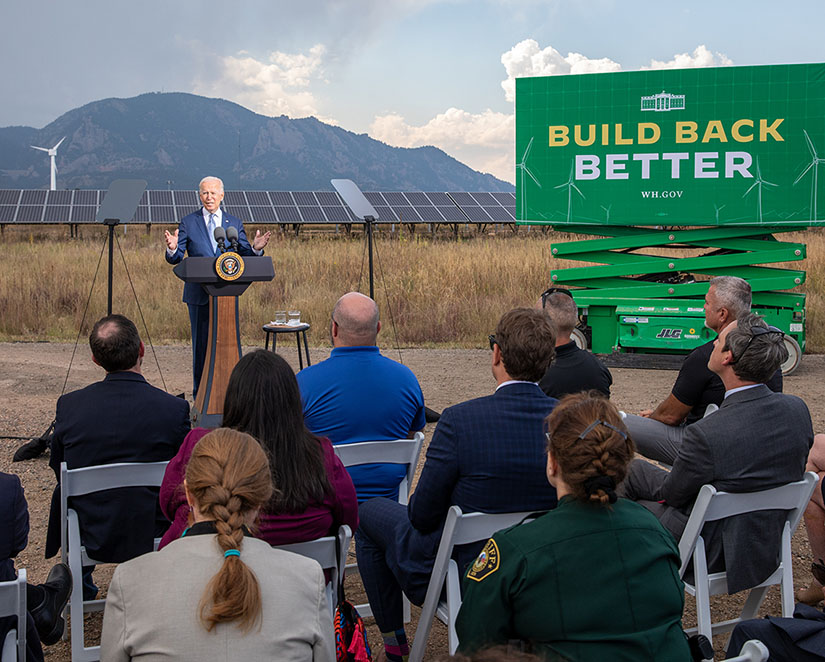 President Biden speaks to a small group near a sign that reads "Build Back Better."