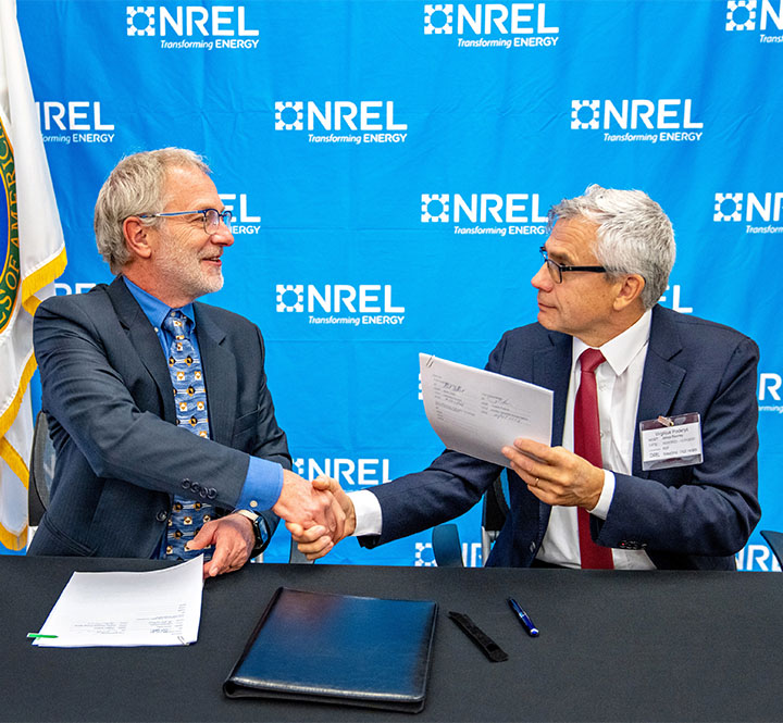 Two men shake hands after signing an agreement