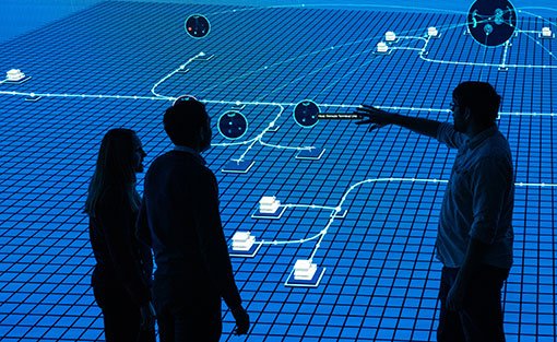 Two people point and look at screen of mapped out grid network