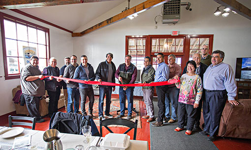 Group of people stand inside building during ribbon cutting ceremony