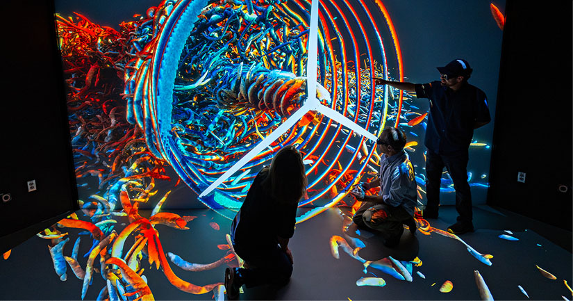 People standing in front of large display screen showing a 3D image of a spinning turbine