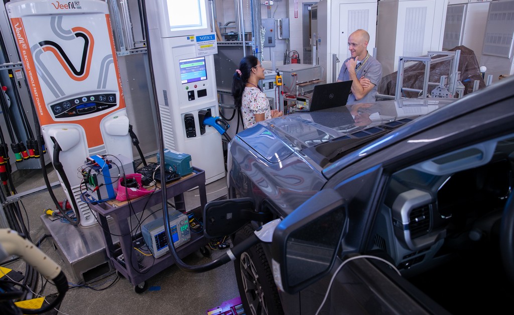 Photo of two people researching an electric vehicle while it charges