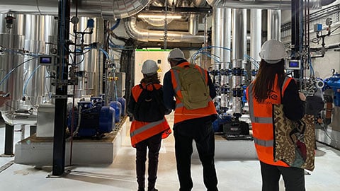 Group of people looking at tubes in the inside of a geothermal power plant