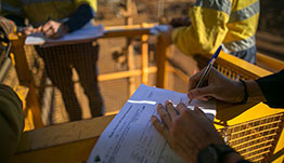 Hand filling out form at safety site.