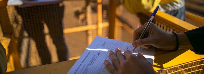 Hand filling out form at safety site.