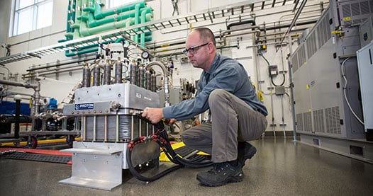 Photo of a man working with a hydrogen electrolyzer in a laboratory