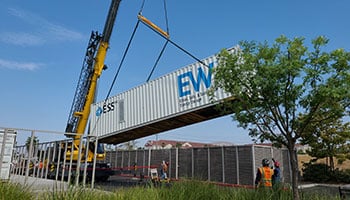 Rectangular storage unit being lowered by crane on a job site