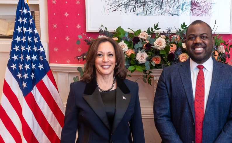 Two people stand alongside the American flag