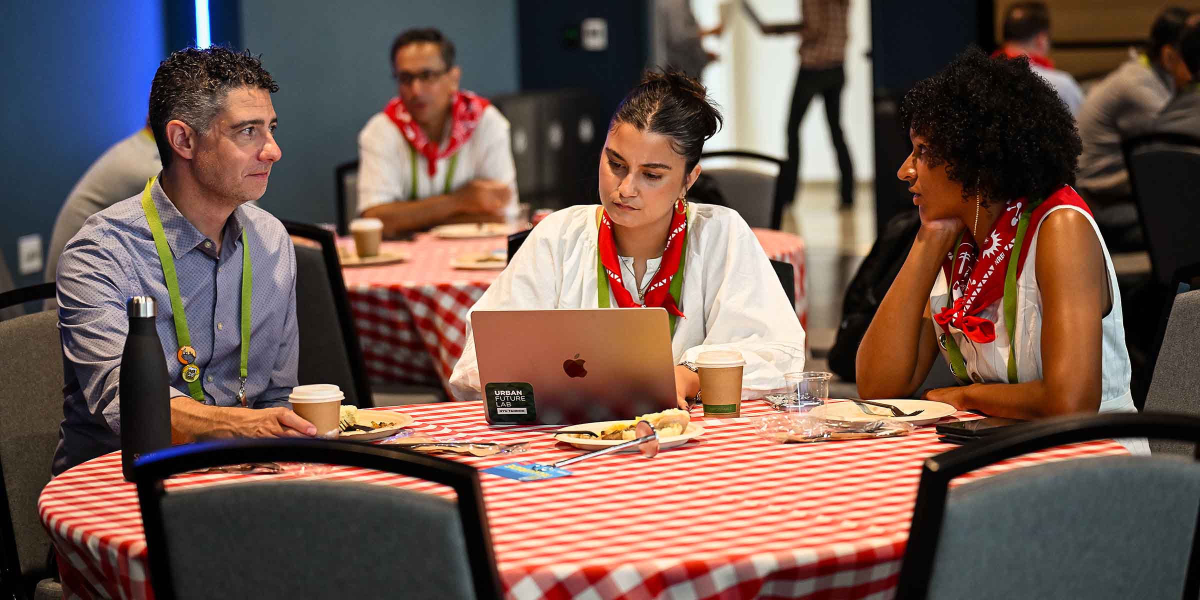 Three people talk around a table in a conference room.