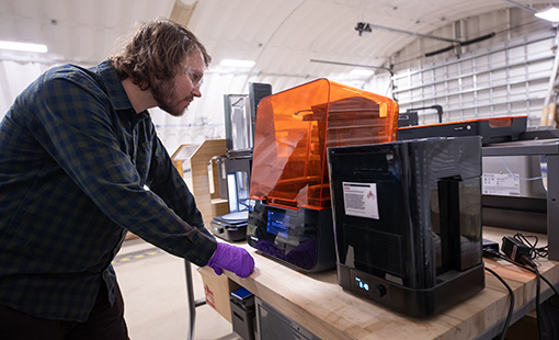 casey-nichols-3dprint-79216 Researcher examines a 3D printer in process.