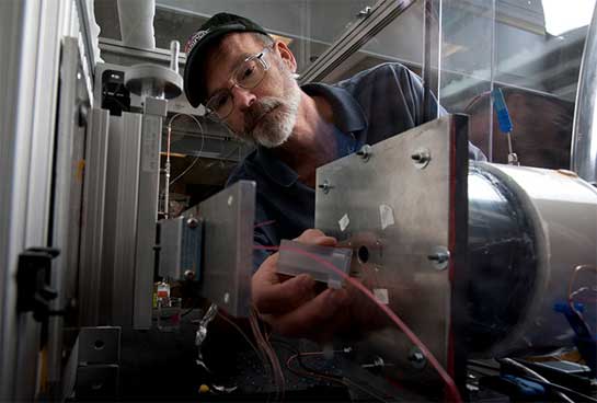 photo-peem-lab-20028 Photo of a man adjusting equipment in a lab, specifically an air-cooling test bench.
