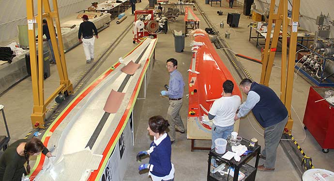 research-wind-41769 A birds-eye view of a large manufacturing facility, with people performing various activities across the image.