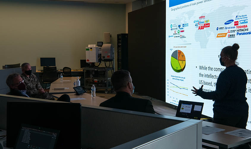 supply-chain-energy-security-samanthareese-nrel-dennis-schroeder-63829-center A woman presents in front of a screen to three people in medical masks.