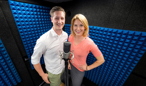 80381 Two people standing side by side in a dark room, smiling