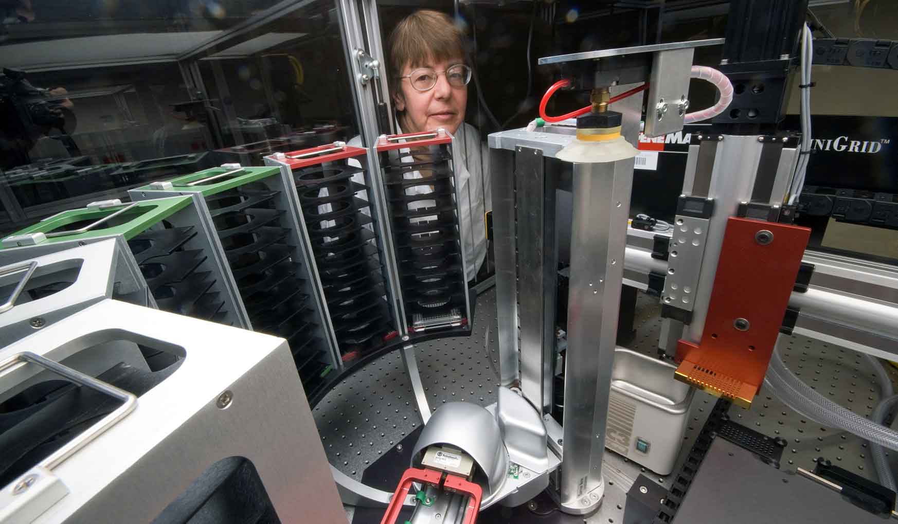 A woman in a lab holding a glass container with algae.