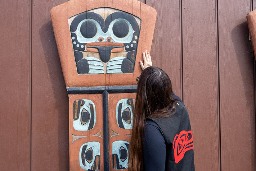 20250507-nrel-partners-with-chilkat-indian-village-to-improve-housing-in-klukwan-alaska-carving-shawna A person places their hand on a carving.