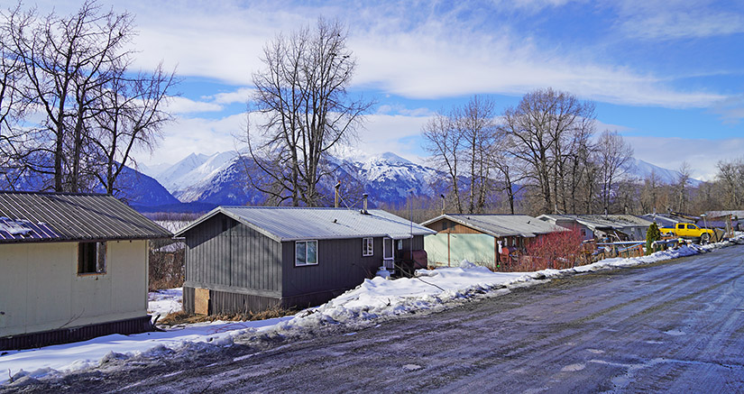 20250507-nrel-partners-with-indian-village-to-improve-housing-in-klukwan-alaska-houses A row of homes with mountains in the background.