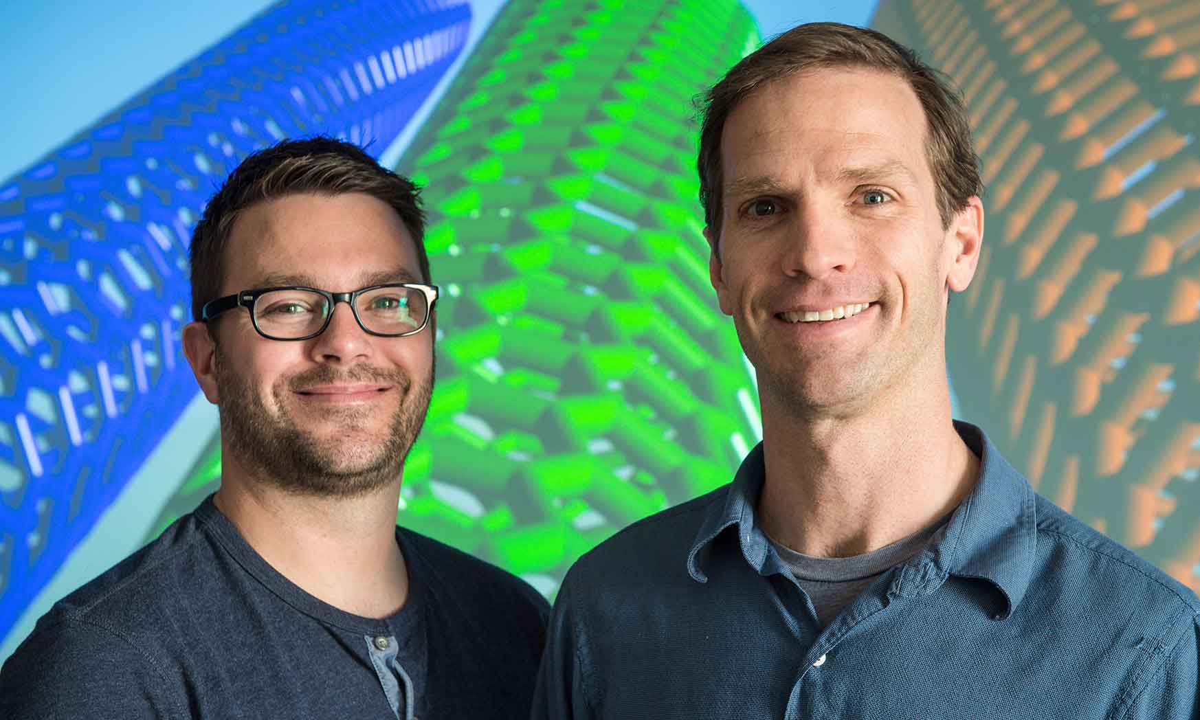 Two men stand in front of a screen that shows carbon nanotubes.