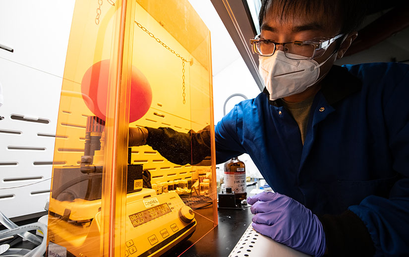 A researcher works with scientific UV light equipment in a lab.