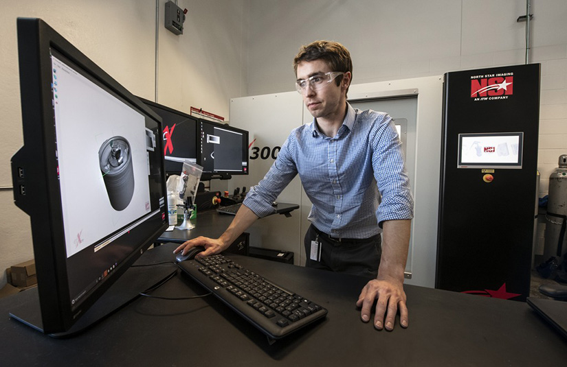 Photo of a researcher standing at a computer in a lab