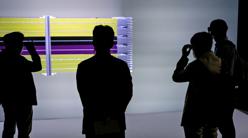 Four silhouettes stand in front of a digital display.