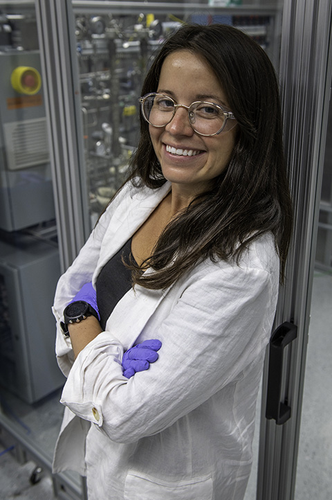 A woman wearing gloves and glasses poses in a lab.
