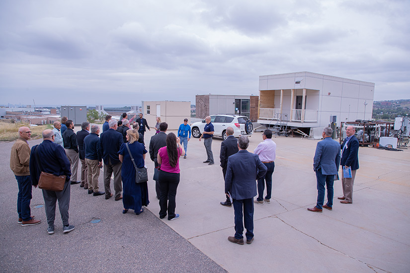 20250414-modular-construction-enables-efficient-and-affordable-housing-group-72013 Shanti Pless speaks to a group of people in front of a modular apartment prototype.