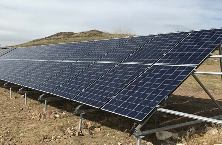 Photo of blue solar panels mounted on the ground.