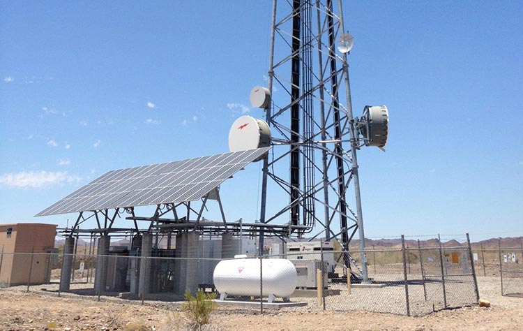 Photo of a solar panel in front of a communications tower.