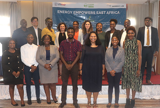 A group of 17 people pose in front of a banner with the words Energy Empowers East Africa.