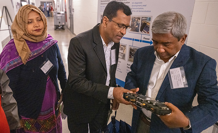 Three people looking at a device.