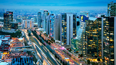 Aerial view of bustling freeway and city scrapers at night.