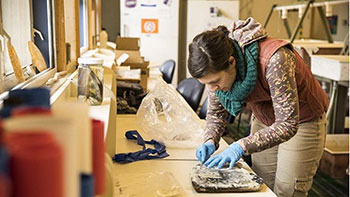 202405-career-in-marine-energy Person bends over work table to fix marine energy components