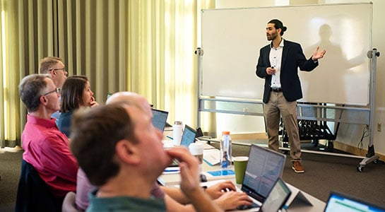 A man speaking in front of a class.