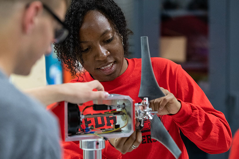 Two people work on a wind turbine model