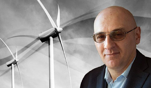 Vahan Gevorgian in sunglasses standing in front of solar photovoltaic panels and a wind turbine