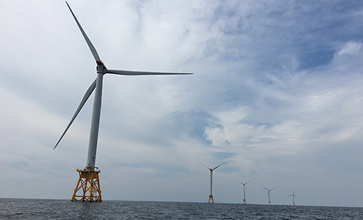 Wind turbines in a line in the ocean.