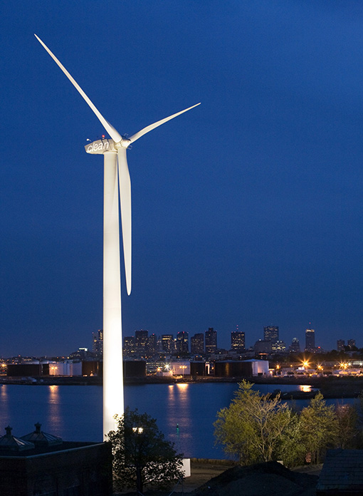 An illuminated wind turbine at night.