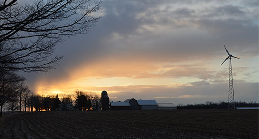 Wind turbine on a farm at sunset