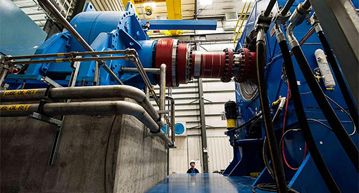 Photo of large blue and red test machinery with a man looking up at it.