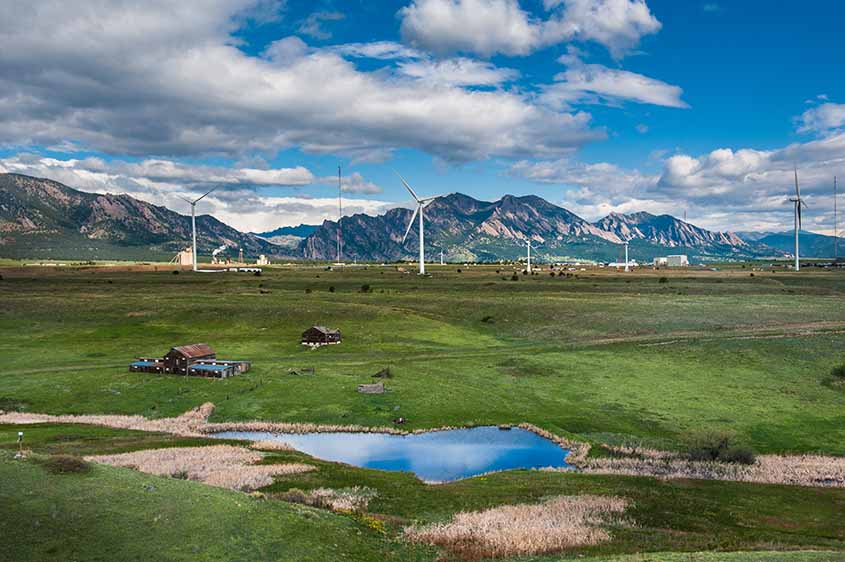 An aerial photo of the NREL Flatirons Campus with wind turbines on a plain in front of mountains