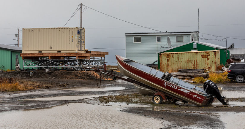 A boat on a sand with buildings in the background.