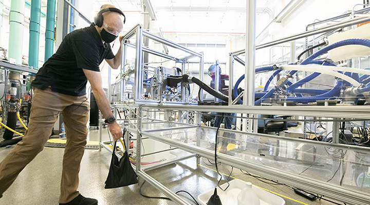 Person places sandbag on lab equipment inside facility