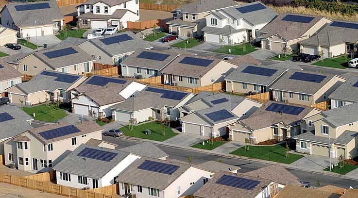 Four rows of houses, each with solar panels on their roofs.