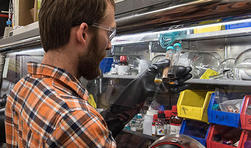 A man in a lab holds up three vials.