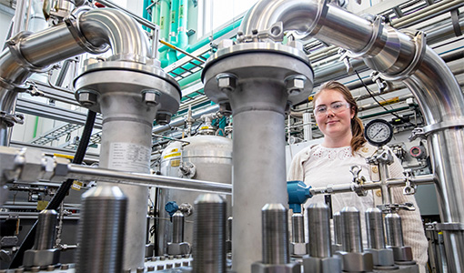 A researcher surrounded by pipes in a laboratory