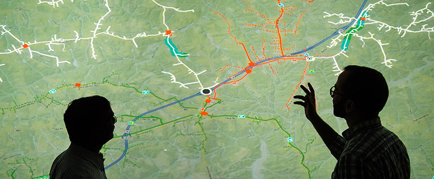 Two researchers look at a power grid projection.