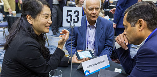 Three people talk while seated at a table.