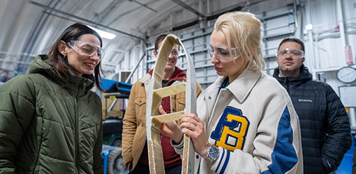 One person holds a wooden object while three others stand beside them.